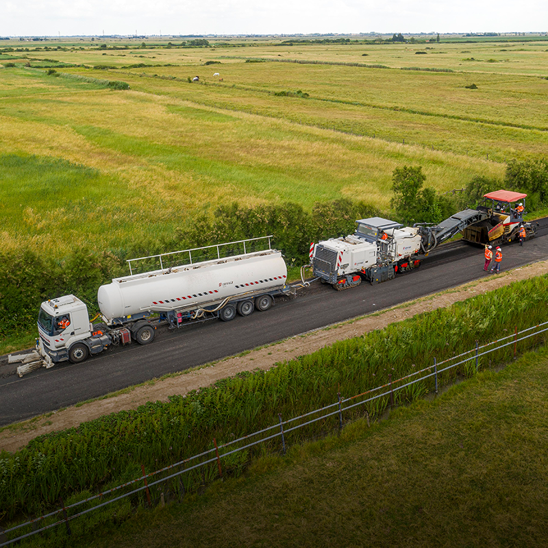 Vista aérea de maquinaria extendiendo asfalto sostenible en una carretera en España para su conservación viaria